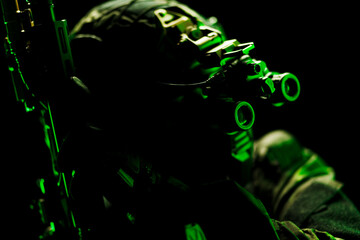 Close-up of military gear and night vision goggles in green illumination