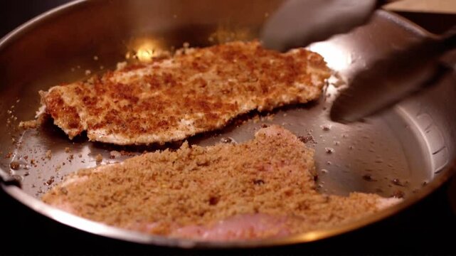 escalopes de dindes pan&eacute;s maison, sur une po&ecirc;le en acier inoxydable chaude, puis retournement des escalopes &agrave; l'aide d'une pince de cuisine