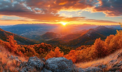 A panoramic view capturing the sunset over a mountain range in autumn