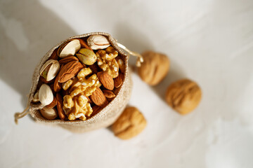 Mix of different nuts in a burlap sack. Jewish holiday Tu Bishvat concept on white background with copy space