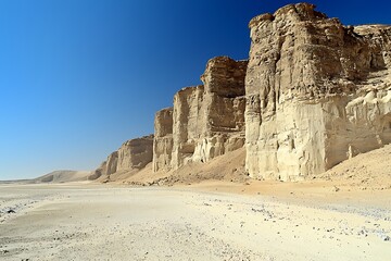 A dramatic desert landscape with towering sandstone formations under a clear blue sky