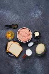 Prepared ingredients for cooking chicken cutlets on a black concrete background. Ingredient layout. Step-by-step recipes.