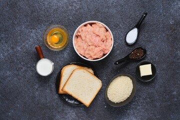 Prepared ingredients for cooking chicken cutlets on a black concrete background. Ingredient layout. Step-by-step recipes.