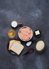 Prepared ingredients for cooking chicken cutlets on a black concrete background. Ingredient layout. Step-by-step recipes.