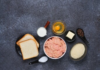 Prepared ingredients for cooking chicken cutlets on a black concrete background. Ingredient layout. Step-by-step recipes.