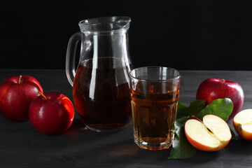 Tasty fresh apple juice and fruits on black wooden table