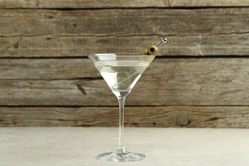 Martini cocktail with olives in glass on light table