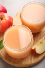 Tasty apple juice in glasses and fresh fruits on grey table, closeup