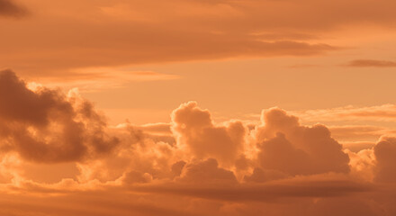 Fototapeta premium Golden Hour Cloudscape: Dramatic Sunset Sky with Orange and Brown Cumulus Clouds