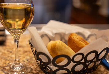 Bred in the basket and a glass of white wine on the table. Close-up, selective focus