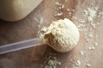 Whey protein powder in a measuring cup on a table
