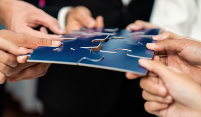 Multiethnic business people holding jigsaw pieces and merge them together as effective solution...