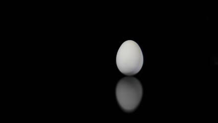 Egg on black background with its reflection.