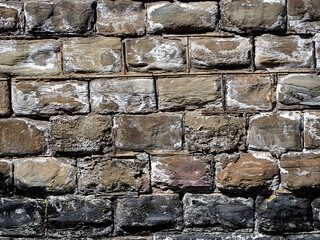 Vintage stone background. The wall is made of molded stone blocks. Old bricks are different in color due to white coating and old paint. Texture of old stonework.