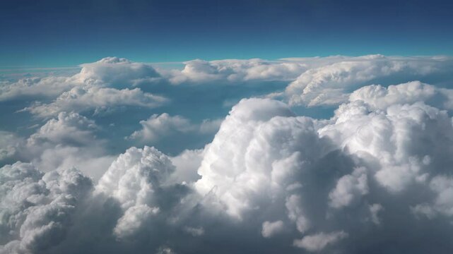 
An enchanting aerial video capturing the breathtaking view of thick, fluffy clouds stretching endlessly below, seen from a plane window during a peaceful flight under a clear blue sky