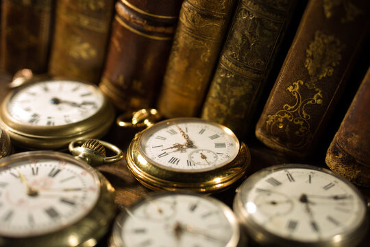 Set of old antique clocks on table with ancient books. The covers of a very old books.
