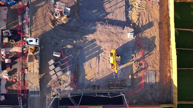 Aerial view from drone at Construction site progress near downtown with heavy machinery at work during daylight hours
