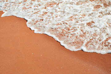 Foamy ocean waves washing over golden sand on a sunny day