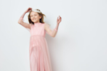 Naklejka premium Happy girl in a pink dress dancing against a light background, embodying joy and innocence, perfect for seasonal themes and children s fashion