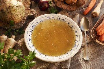 Chicken bone broth in plate with ornaments on a wooden table
