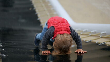 Active little baby boy toddler at playground park climbing slider