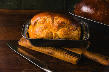 Sweet brioche bun in a bread baking pan, on a dark background. Delicious homemade pastries