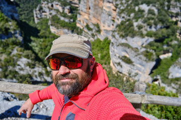 A man in cap and beard taking a selfie from a viewpoint