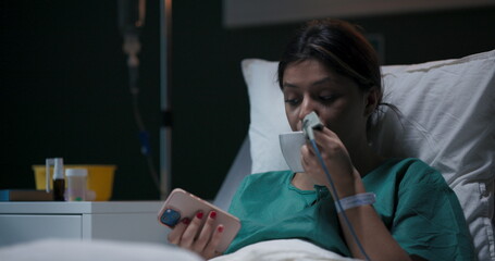 Patient reclining in hospital room, wearing nasal oxygen tube, having a video conversation.