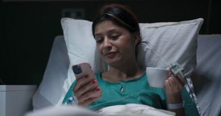 Young patient resting in hospital bed, oxygen tube in her nose, talking on video call.