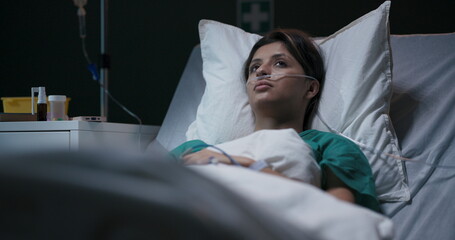 Exhausted young female patient in hospital ward with tube in nose.