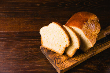 Delicious and sweet buttery bread cut into slices on a dark wooden cutting board. Delicious home baked goods