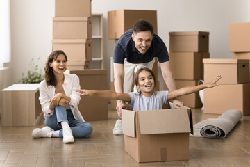 Funny excited family playing on relocation day, daddy push cardboard box with seated inside little daughter, take break, enjoy playtime during relocation day to new house, exuding happiness and joy