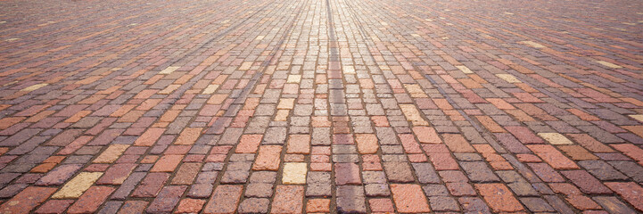 Colorful brick pavement with weathered texture in sunlight
