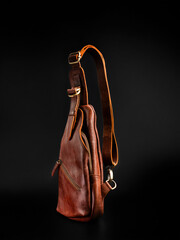 Blank brown leather sling bag isolated on black background, perfect for leather company catalog...