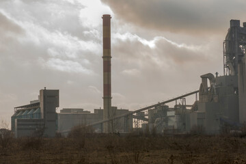 Zakład przemysłowy - cementownia - na tle ciemnych chmur w takim postapokaliptycznym klimacie. Cementownia na tle chmur wygląda trochę jak z gier (i książek) o poszukiwaniu artefaktów w Zonie . © Grzegorz