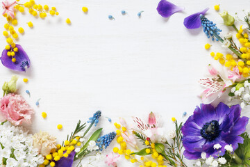 White wooden background with spring colorful flowers and copy space. Decorative floral greeting...