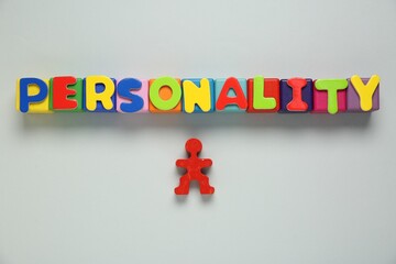 Word Personality made of colorful letters and red human figure on light grey background, top view