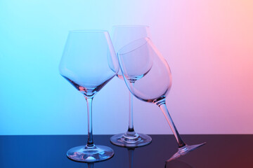 Empty glasses on table against color background