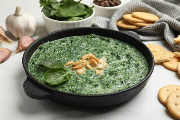 Delicious spinach sauce with peanuts and crackers on white table, closeup