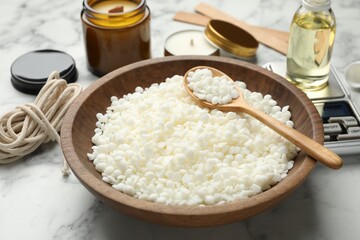 Soy wax and other supplies for making candles on white marble table, closeup