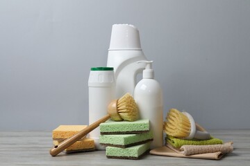 Eco-friendly cleaning products and supplies on wooden table against grey background