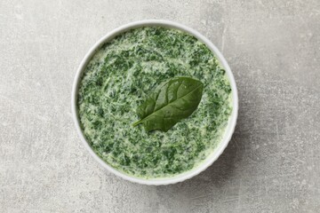 Delicious spinach sauce on grey table, top view