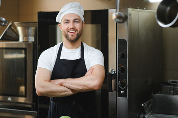 Portrait of a smiling male chef with cooked food standing in the kitchen