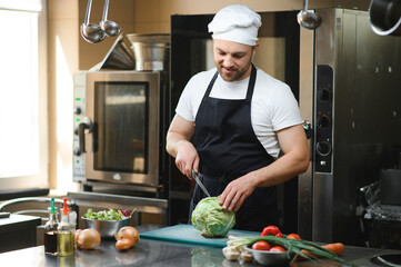 Portrait of a smiling male chef with cooked food standing in the kitchen