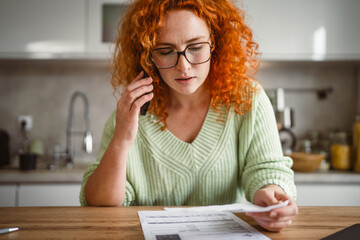 Adult woman have a phone call about bills and tax in the kitchen