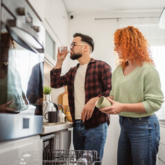 boyfriend help girlfriend to put dishes in dishwasher in kitchen