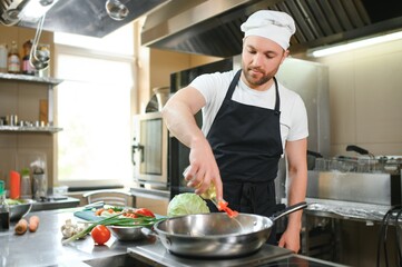Portrait of happy caucasian male chef standing in restaurant kitchen, copy space