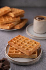 photo Savory golden waffles served with a creamy cup of coffee on a cozy breakfast table setting for a delightful morning experience with delicious brunch treats