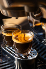 Two glasses of freshly brewed espresso coffee with crema made by an espresso machine