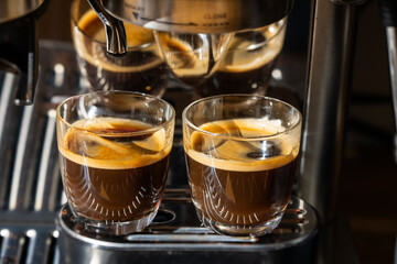Two glasses of freshly brewed espresso coffee with crema made by an espresso machine
